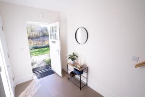 um corredor branco com um espelho e uma mesa em Longwater Avenue em Reading
