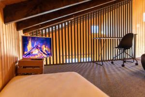 a bedroom with a tv and a chair and a desk at Ferienwohnung im Chalet am Bach in Schwarzsee