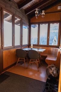 a dining room with a table and chairs and windows at Ferienwohnung im Chalet am Bach in Schwarzsee