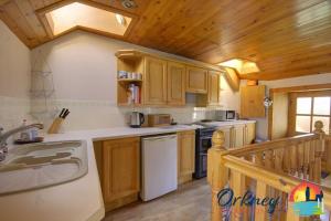 eine Küche mit Holzschränken und einem weißen Geschirrspüler in der Unterkunft Khyber Pass Cottage, Stromness - OR00332F in Stromness