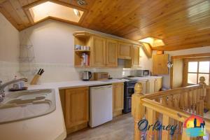 a kitchen with wooden cabinets and a white dishwasher at Khyber Pass Cottage, Stromness - OR00332F in Stromness