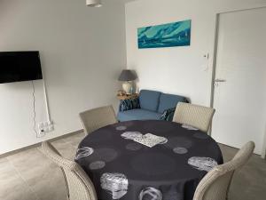 a dining room with a table with chairs and a couch at Repos paisible in Talmont