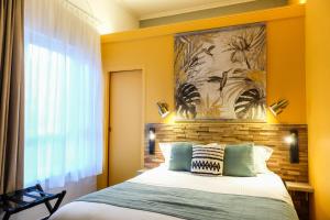 a bedroom with a bed and a painting on the wall at Hôtel Le Patio - Deauville in Deauville