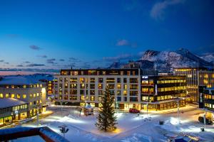 a building with snow covered mountains in the background at Nordis Apartments in Svolv&aelig;r