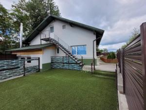 a white house with a fence and a yard at MIG HOME in Horezu