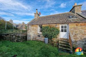 een stenen cottage met een witte deur en een raam bij Khyber Pass Cottage, Stromness - OR00332F in Stromness