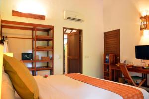 a bedroom with a bed and a desk and a television at Cocotinos Sekotong Lombok in Sekotong