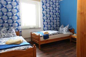 2 camas en una habitación con paredes azules y ventana en Waldpension Droyßig, en Droyßig