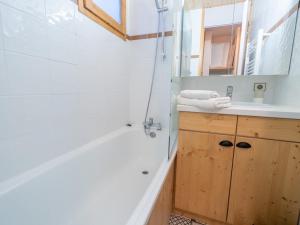 ein Badezimmer mit einer Badewanne, einem Waschbecken und einem Spiegel in der Unterkunft Studio Les Avanchers-Valmorel, 1 pièce, 4 personnes - FR-1-291-843 in Valmorel