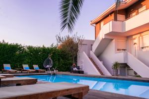 a swimming pool with tables and chairs next to a building at Kapahi Seaview Hotel Apartments in Potos