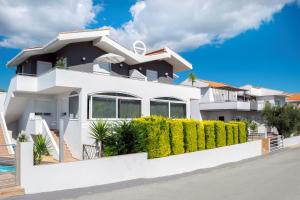 a white house with a white fence and bushes at Kapahi Seaview Hotel Apartments in Potos