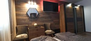 a bedroom with a bed and two chairs and a tv at Апартамент Bella Casa in Beli Iskar