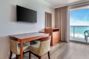 a room with a desk with chairs and a television at Ramada Plaza by Wyndham Marco Polo Beach Resort in Miami Beach