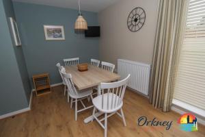 Algarth, Stromness, Orkney - OR00218F في سترومنيس: غرفة طعام مع طاولة وكراسي خشبية