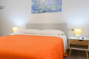 a bedroom with a bed with an orange bedspread and two lamps at Le stanze di Mami in Salerno