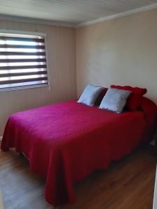 une chambre avec un lit avec une couverture rouge et une fenêtre dans l'établissement Casa Santa María, à Pichilemu 8 autres photos