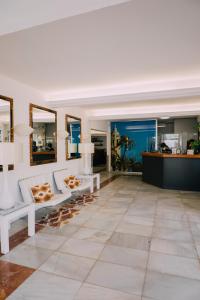 un vestíbulo con bancos blancos y un mostrador en Hotel Subur Maritim, en Sitges