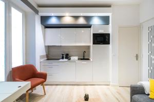 a kitchen with white cabinets and a red chair at Frontière de Monaco - Appartement neuf - AM in Beausoleil +17 photos