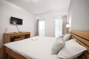 um quarto com uma cama com lençóis brancos e uma televisão em Sunset Boutiqe Apartment Old Town Zadar em Zadar