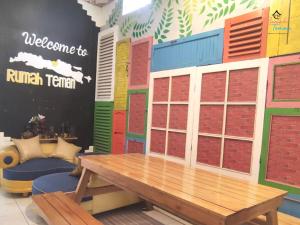 a room with a wooden table and a wall with windows at Rumah Teman Hostel in Semarang
