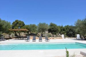a swimming pool with lounge chairs and a umbrella at Trullo Fragnelli in Cisternino