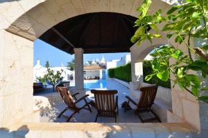 een patio met 4 stoelen en een tafel in een boog bij Villa Giovanna Trullo in Ostuni