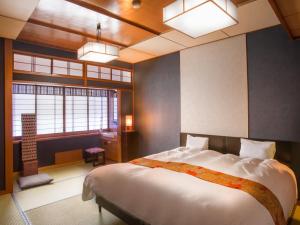 a bedroom with a large bed and a window at Kinosaki Onsen Hanakouji Saigetsu in Toyooka