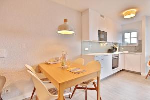 Il comprend une cuisine et une salle à manger avec une table et des chaises en bois. dans l'établissement Residenz Ostseestrand Residenz Ostseestrand Appartement 17, à Scharbeutz