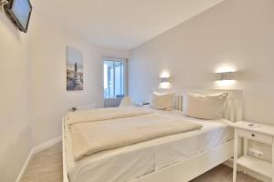 沙博伊茨Residenz Ostseestrand Appartement 17的白色卧室配有一张大床和一张书桌 更多28张照片