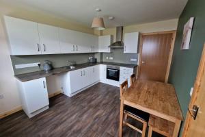 a kitchen with white cabinets and a wooden table at 18 Gold Drive, Kirkwall, Orkney - OR00185F in Orkney