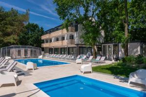 a swimming pool with lounge chairs next to a building at M2 Resort Wellness & Spa in Ostrowo