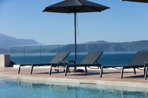 twee stoelen en een parasol naast een zwembad bij Pietra Di Mare in Petres