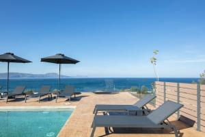 a pool with chairs and umbrellas next to the ocean at Pietra Di Mare in Petres