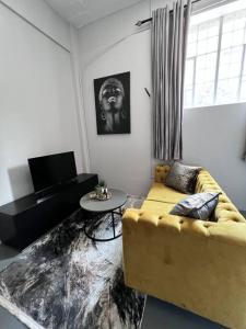 sala de estar con sofá amarillo y mesa en `Luxury Cosy City Apartment, en Johannesburgo