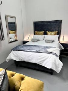 1 dormitorio con 1 cama grande y espejo en `Luxury Cosy City Apartment, en Johannesburgo