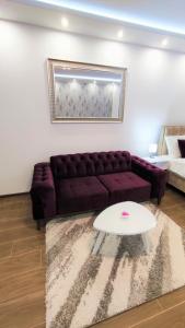 a living room with a purple couch and a table at Apartman Vivaldi - CENTAR in Vrnjačka Banja