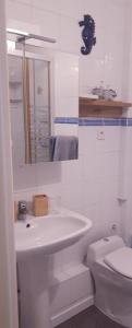 Baño blanco con lavabo y aseo en Les Ondines, en Estréelles
