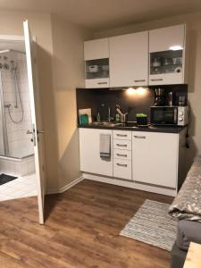 uma cozinha com armários brancos e um lavatório em GottwaldHaus-Freiberg-Apartment / A em Freiberg