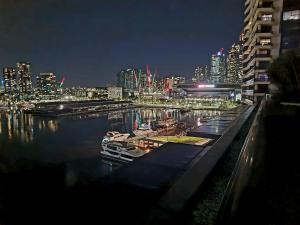een stad 's nachts met boten in het water bij Luxe Waterfront Melbourne in Melbourne