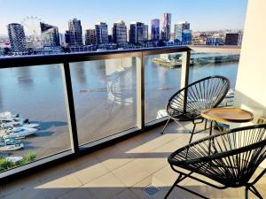 a balcony with chairs and a view of the water at Luxe Waterfront Melbourne in Melbourne