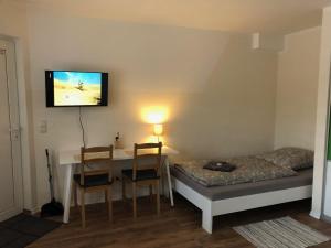 um quarto com uma mesa e uma cama e uma televisão na parede em GottwaldHaus-Freiberg-Apartment / A em Freiberg