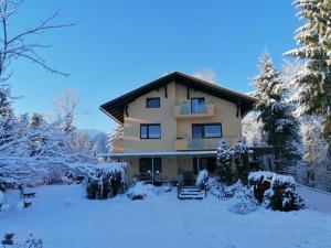 una casa grande en la nieve con árboles en Haus am Wald, en Faak am See
