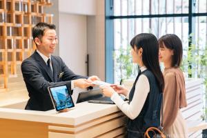 a man and a woman standing at a cash register at Keio Prelia Hotel Kyoto Karasuma-Gojo in Kyoto