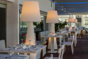 un restaurante con mesas blancas, sillas y luces en Odessa Beach Hotel, en Protaras