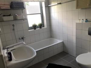 a white bathroom with a tub and a toilet at Modernes Architektenhaus am Jadebusen in Varel