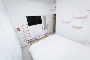 um quarto branco com uma televisão e uma cómoda branca em אירוח בגולן em Katzrin