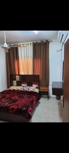 a bedroom with a red bed and a piano at Abo Amer Apartments in Aqaba