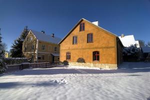 une grande maison en bois avec de la neige au sol dans l'établissement Horská chalupa Jeřabina, à Horní Blatná
