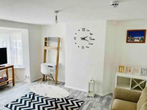 a living room with a clock on the wall at Fabulous, Spacious, Newly Refurbished Home close to Heathrow Airport in Hayes