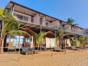 a building on the beach with chairs and palm trees at Madhu Huts Agonda in Agonda